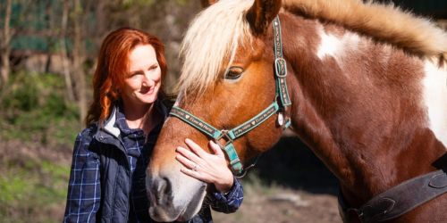 Woman stands with horse as in Georgetown, Kentucky, getting ready to horseback ride through the Kentucky backwoods.